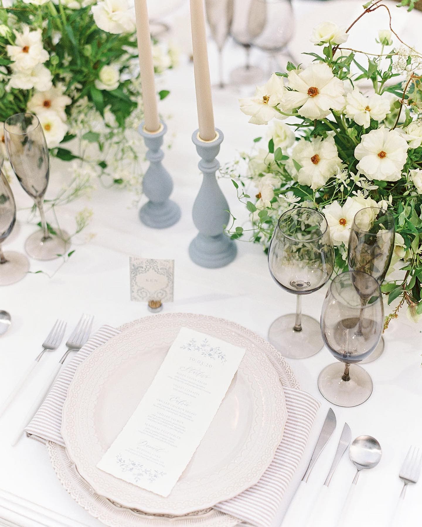 A beautifully set dining table with floral arrangements, candles, and elegant tableware.