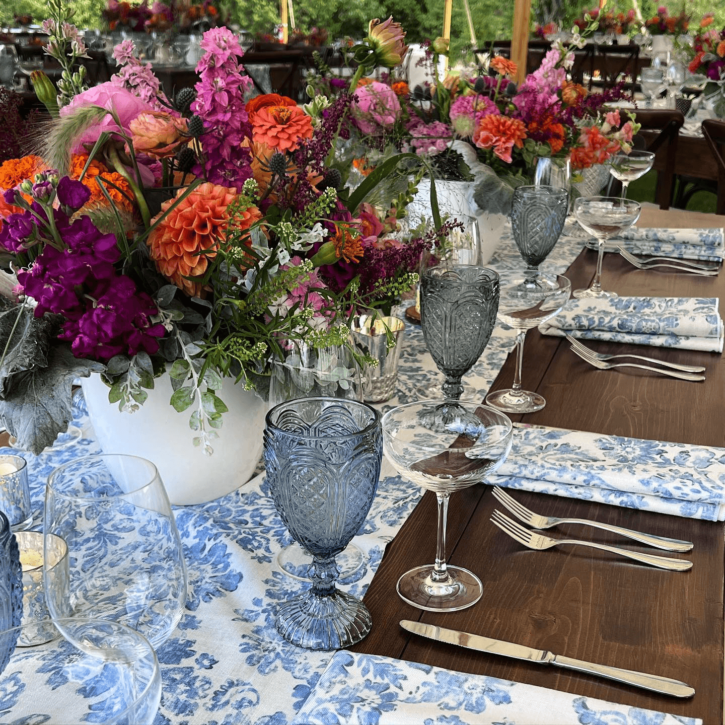A beautifully arranged dining table featuring floral centerpieces, elegant glassware, and patterned linens.