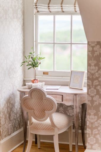 A cozy corner featuring a decorative desk with a floral chair and a view out the window.